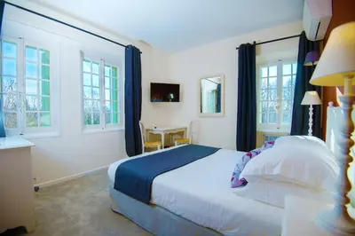 a bedroom with a bed and a table and windows at Demeures et Châteaux Hôtel L'Hermitage in Pernes-les-Fontaines