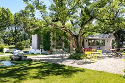 a backyard with chairs and tables under a tree at Demeures et Châteaux Hôtel L'Hermitage in Pernes-les-Fontaines