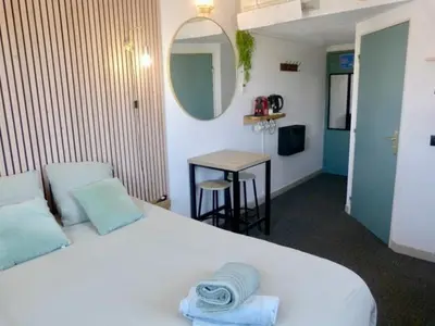 a bedroom with a bed and a table and a mirror at Joli Studio le clos d'Aix avec grande terrasse piscine et parking gratuit in Aix-en-Provence