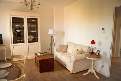 a living room with a white couch and a table at La maison du bassin in LʼIsle-sur-la-Sorgue