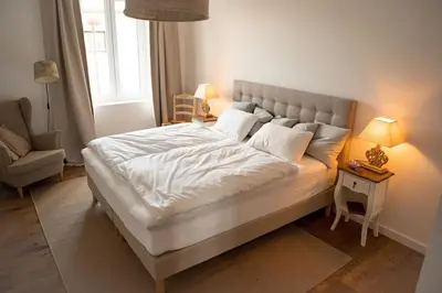 a bedroom with a large white bed and a chair at La maison du bassin in LʼIsle-sur-la-Sorgue
