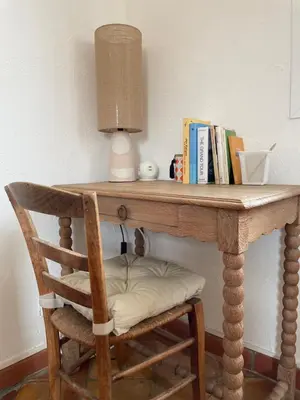 a table with a lamp and a chair with books at 2 pièces climatisé en duplex avec terrasse in Aix-en-Provence