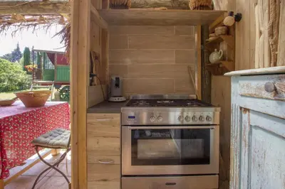 a kitchen with a stove in a wooden cabin at Vent de Bohème in Cabannes