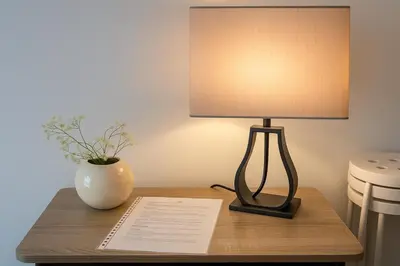 a lamp on a table with a vase and a paper at Maison, Jardin, piscine parking près d'Aix Centre in Venelles