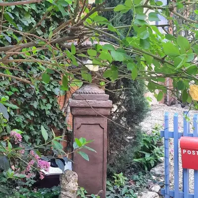 a stone pillar in a garden next to a fence at Gite Au fond du jardin in Saint-Saturnin-lès-Avignon