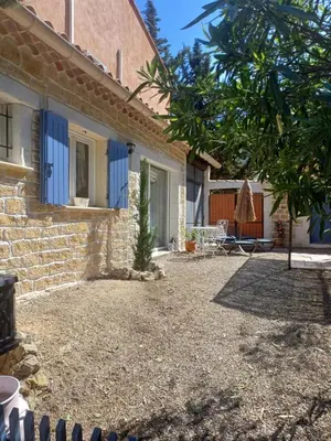 a brick house with blue shutters and a patio at Gite Au fond du jardin in Saint-Saturnin-lès-Avignon