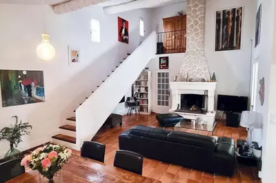 a living room with a staircase and a fireplace at Villa tout confort, piscine - Au pied du VENTOUX in Saint-Didier