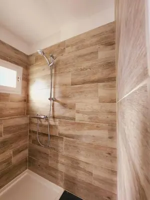 a bathroom with a shower with wooden walls at Bienvenue à L'ÉCRIN avec piscine privée in LʼIsle-sur-la-Sorgue