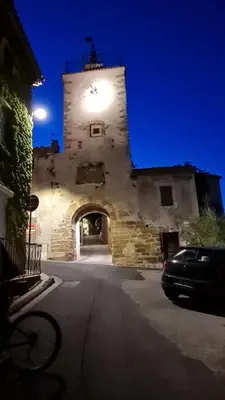 a building with a clock tower with a car parked in front at La calade in Vedène