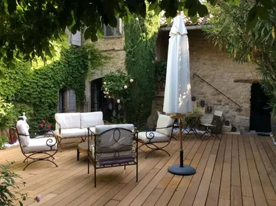 a patio with an umbrella and chairs and a table at La Maiz in Maubec