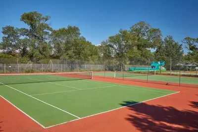 a tennis court with a playground in the background at MOBIL HOME LMNP GUIGON in La Roque-dʼAnthéron