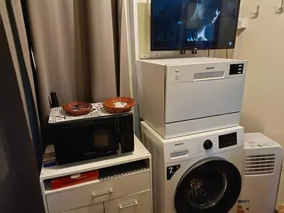a laundry room with a microwave and a tv at MOBIL HOME LMNP GUIGON in La Roque-dʼAnthéron