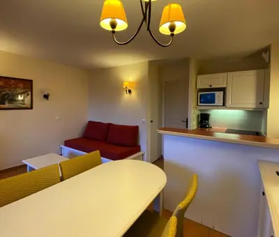 a living room with a table and a red couch at Village Pont Royal en Provence - maeva Home - Appartement climatisé 2 pièces 6 personnes - Confort MAE-1684 in Mallemort