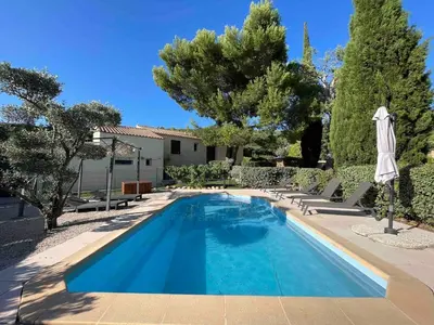 a swimming pool with chairs and an umbrella and trees at Villa avec Piscine au coeur de la campagne provençale in Lançon-Provence