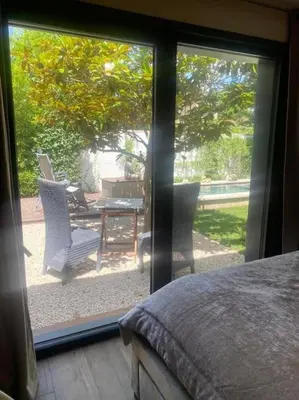 a bedroom with a view of a patio with a table and chairs at A lombre du magnolia in LʼIsle-sur-la-Sorgue