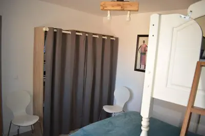 a bedroom with a bed with a curtain and two chairs at Le mas de la joëlette in Vedène