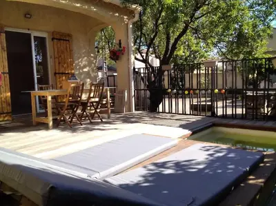 a patio with a pool and a table and chairs at Le mas de la joëlette in Vedène