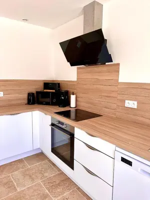 a kitchen with white cabinets and a flat screen tv at Maison de charme avec Jacuzzi in Mollégès