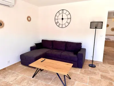 a living room with a couch and a clock on the wall at Maison de charme avec Jacuzzi in Mollégès