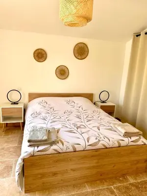 a bed in a bedroom with two lamps on the wall at Maison de charme avec Jacuzzi in Mollégès