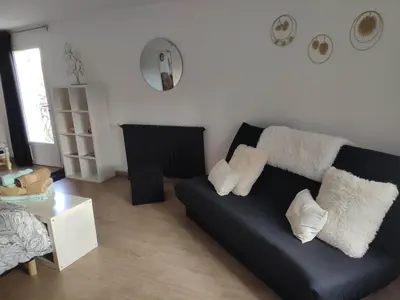 a living room with a black couch and a table at La Tourelle Suite Cosy entre vignoble aixois et Luberon in Le Puy-Sainte-Réparade