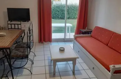a living room with a red couch and a table at Belle Maisonette dans Residence 3* avec piscine partagée in Saint-Saturnin-lès-Avignon