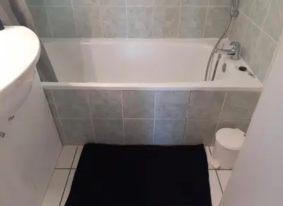 a small bathroom with a tub and a black rug at Belle Maisonette dans Residence 3* avec piscine partagée in Saint-Saturnin-lès-Avignon