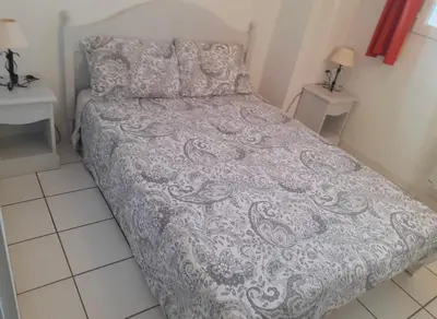 a small bedroom with a bed with a gray comforter at Belle Maisonette dans Residence 3* avec piscine partagée in Saint-Saturnin-lès-Avignon