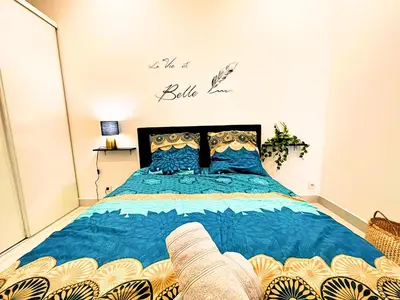 a bedroom with a large bed with a blue comforter at Carré Rouge*Gare Sncf*Fibre Wifi in Miramas