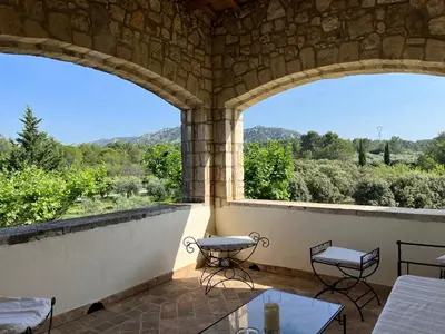 a patio with two tables and a view of the mountains at Chambre d'hôte au cœur de la Provence Eygalieres in Eygalières