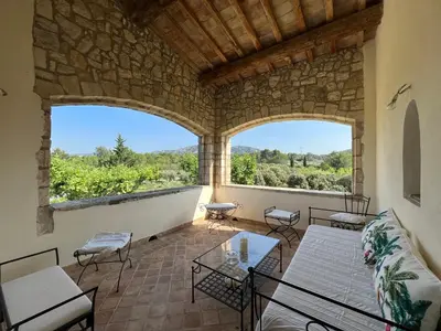 a living room with two large windows and a patio at Chambre d'hôte au cœur de la Provence Eygalieres in Eygalières