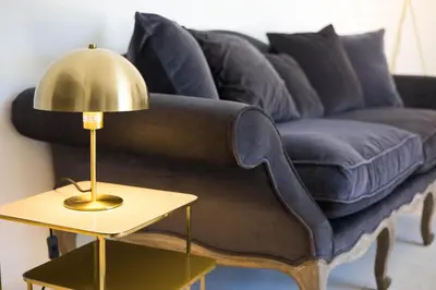 a blue couch with a gold lamp on a side table at Superbe Mas Authentique du Luberon Courroussouvo in Oppède