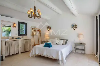 a bedroom with a bed and a table and a chandelier at Superbe Mas Authentique du Luberon Courroussouvo in Oppède