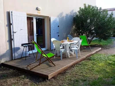 a wooden deck with a table and chairs on it at Maison conviviale à Aubignan avec piscine partagée in Aubignan