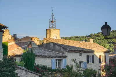 a group of stone houses with a clock tower at Les oliviers in Ansouis