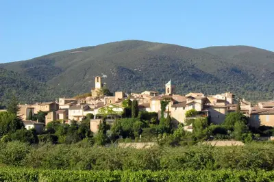 a village on a hill with mountains in the background at Les oliviers in Ansouis