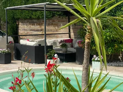 a pool with a pergola and a couch and a palm tree at Villa des palmiers in Saint-Saturnin-lès-Avignon