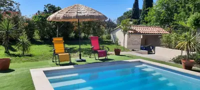 a group of chairs and an umbrella next to a swimming pool at MyLuberon-Appartement au pied du Luberon in Lauris