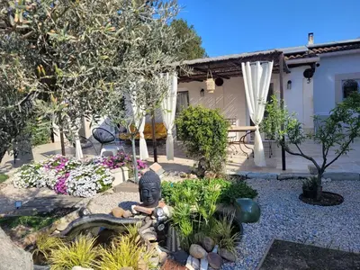 a garden with a statue in front of a house at maisonnette avec piscine la picholine in Châteaurenard