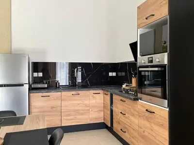 a kitchen with wooden cabinets and stainless steel appliances at maisonnette avec piscine la picholine in Châteaurenard