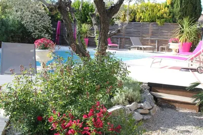 a swimming pool with flowers and a tree in a yard at A l'Orée du Pin in Puyricard