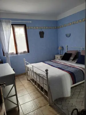 a bedroom with a bed with blue walls at Location saisonnière villa Lauris in Lauris