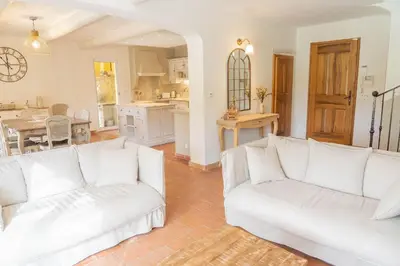 a living room with white couches and a kitchen at Maison à 2 pas du Village D'ansouis à 30 Minutes D'aix-en-provence in Ansouis