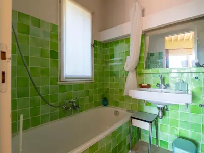 a green tiled bathroom with a tub and a sink at Holiday Home La Tourelle des Ocres by Interhome in Roussillon