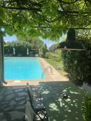 a swimming pool with a table and a lamp at Agréable maison de 65 m2 avec grande piscine in Aix-en-Provence