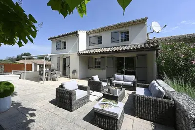 a patio with wicker furniture in front of a house at La Villa Moderna in Robion en Luberon