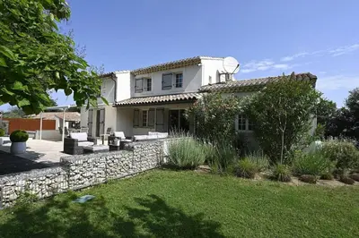 a white house with a stone wall and a yard at La Villa Moderna in Robion en Luberon