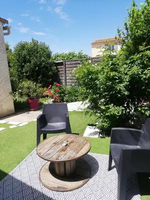a wooden coffee table and chairs on a patio at Petit cocon avec terrasse in LʼIsle-sur-la-Sorgue