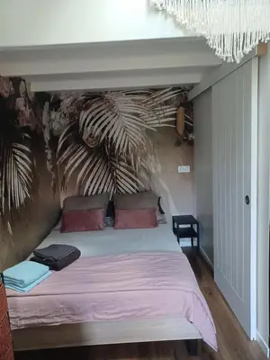 a bedroom with a large bed with a painting on the wall at Petit cocon avec terrasse in LʼIsle-sur-la-Sorgue