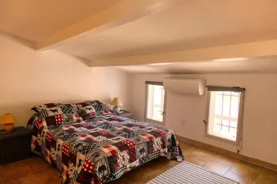 a bedroom with a bed and two windows at Village house of Jean in Gordes